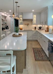 Photo of Island with white counter, wood tone cabinetry, white counter and white cabinets on main run. Charo Hunt Kitchen Design